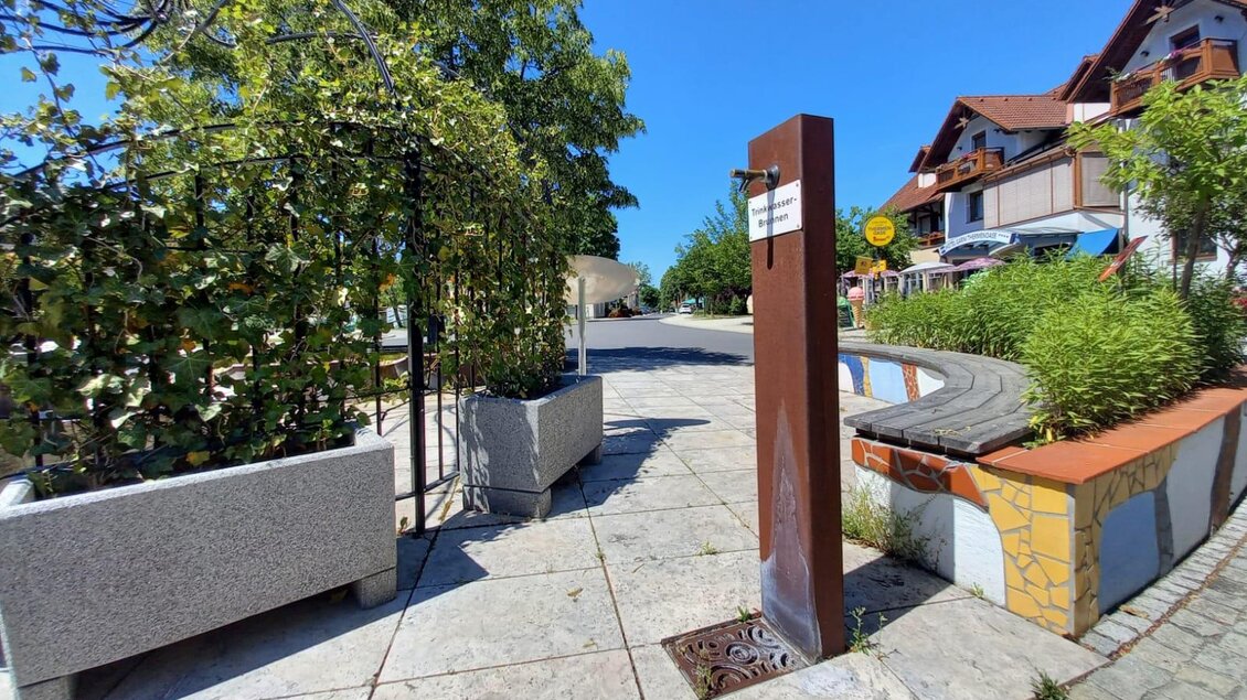 Ein schöner Platz mit Bäumen und einem klaren blauen Himmel. Die Wege sind mit Steinen gepflastert und es gibt Sitzgelegenheiten. | © Thermen- & Vulkanland