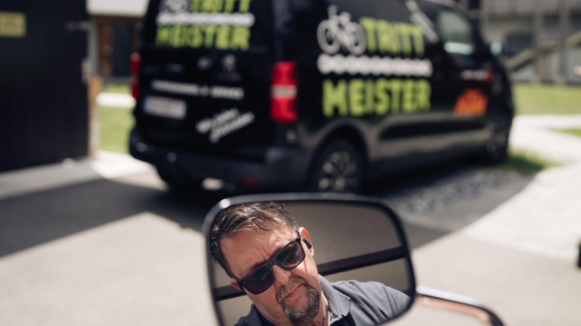 Herr Messner spiegelt sich im Rückspiegel, im Hintergrund steht das Servicefahrzeug von Trittmeister. | © Bernd Grosseck