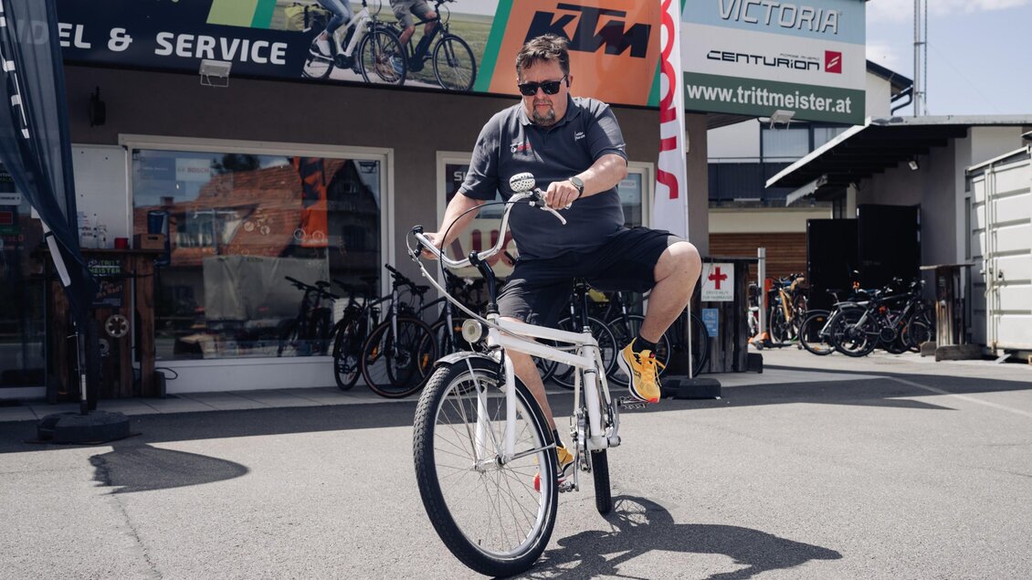 Herr Messner macht eine Probefahrt mit einem weißen Fahrrad vor dem Geschäft Trittmeister in Premstätten. | © Bernd Grosseck