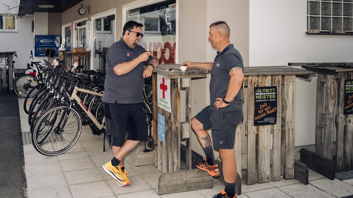 Herr Messner und sein Kollege unterhalten sich bei einer Tasse Kaffee vor dem Fahrradgeschäft Trittmeister in Premstätten. | © Bernd Grosseck