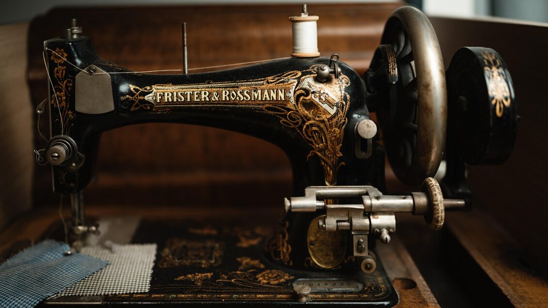 Historische Nähmaschine von Frister & Rossmann mit goldenen Verzierungen und Stoffmustern unter der Nadel. | © Bernd Grosseck