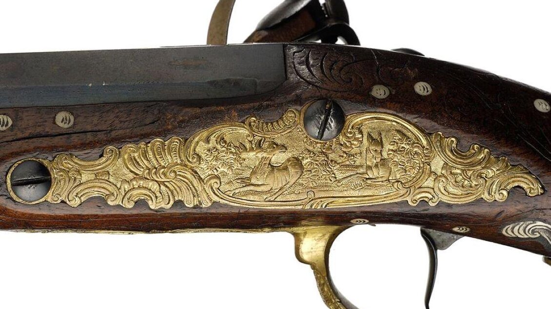 Eine kunstvoll verzierte Waffe mit einem Holzgriff und goldenen Verzierungen. Die Details zeigen Szenen aus der Natur oder Jagd. | © Universalmuseum Joanneum - N. Lackner
