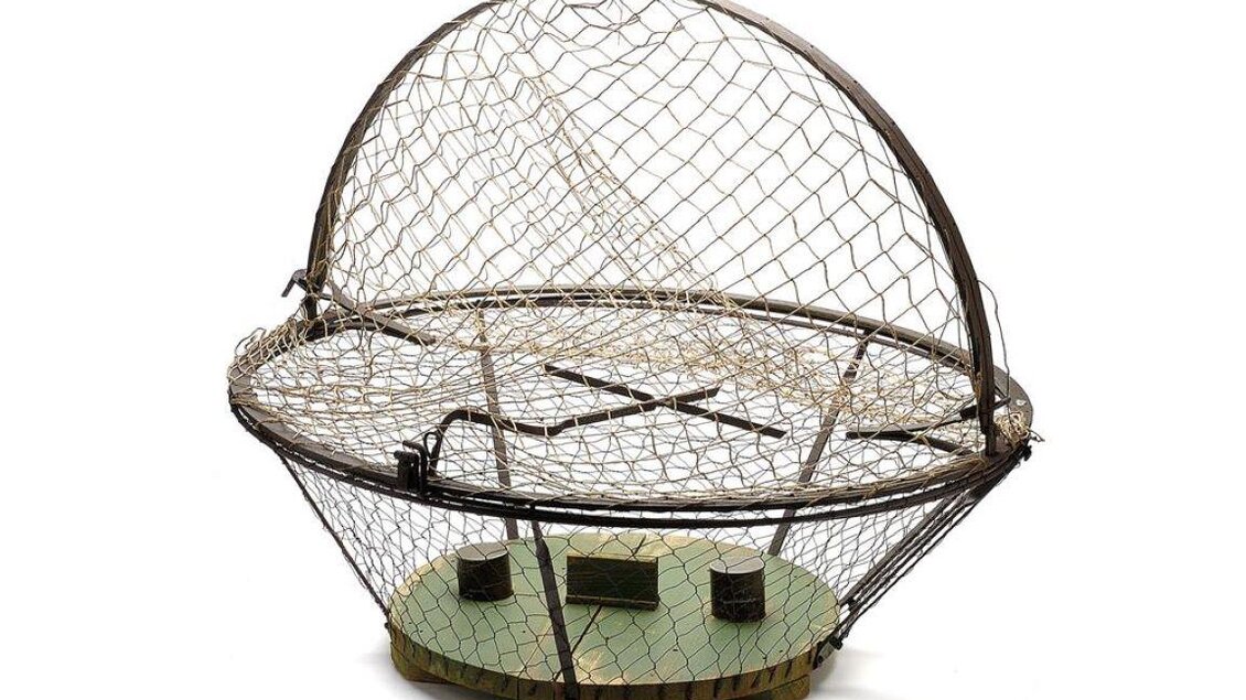 Ein runder Fangkorb mit einem Netz, der auf einer grünen Basis steht. Das Design ist einfach und funktional, ideal zum Fangen von Fischen oder anderen Tieren. | © Universalmuseum Joanneum - N. Lackner