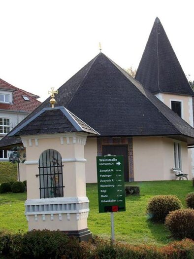 Ein charmantes, kleines Gebäude mit einem scharfen Dach steht an einer Straße. Nebenan befindet sich ein größeres Gebäude mit der Aufschrift "Dolkalschule Retten." | © TV Südsteiermark