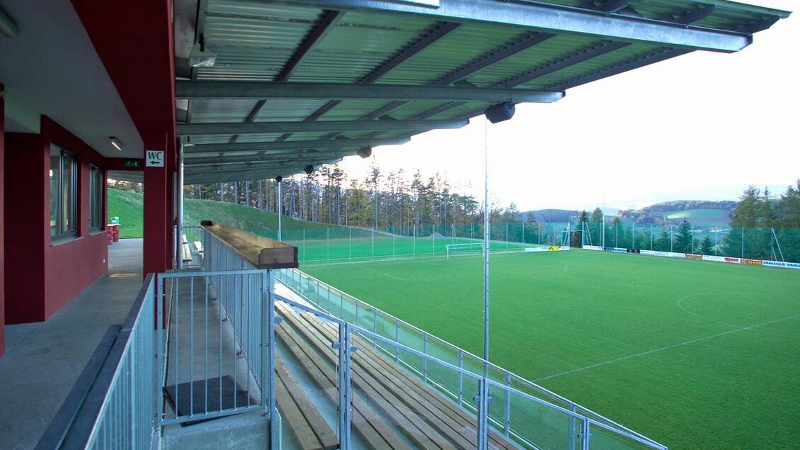 Eine Sportstätte mit einem Rasenplatz und überdachten Sitzplätzen. Im Hintergrund sind Bäume und eine gepflegte Grünfläche zu sehen. | © Gemeinde Pöllauberg