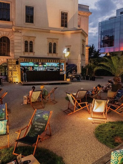Gäste entspannen in der Sommerlounge Viertel 4 in Graz mit Liegestühlen, Bar und Abendstimmung. | © Viertel 4