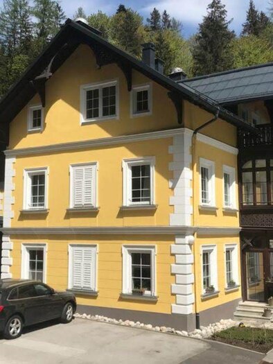 Das schön gelb gestrichene Gebäude mit Holzverkleidung und Fensterläden ist die Villa Styria, ein Hotel in Bad Aussee. Es steht in einer grünen Umgebung mit Bäumen im Hintergrund. | ©  Villa Styria, Bad Aussee