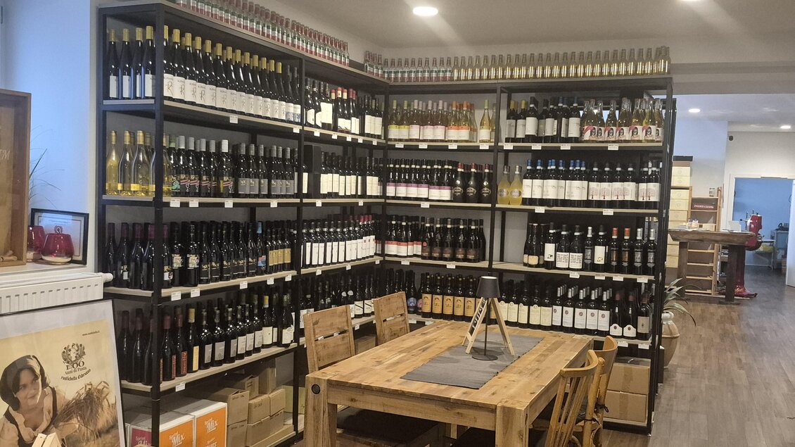 Ein Weinladen mit Regalen voller Weinflaschen. Am Tisch stehen Holzstühle und eine einladende Atmosphäre entsteht. | © TV Hochsteiermark/Andrea Stelzer