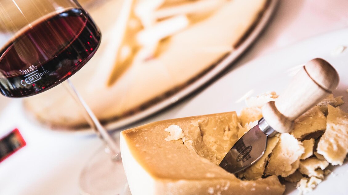 Glas Rotwein und angeschnittener Hartkäse mit Käsemesser bei einer Verkostung in der Vinothek Ellersdorfer in Köflach.  | © Ellersdorfer