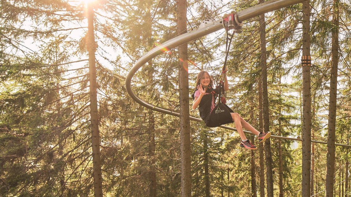 Eine Person fährt auf einer Sommerrodelbahn durch einen Wald. Die Sonne scheint zwischen den Bäumen hindurch. | © Mariazeller Bürgeralpe