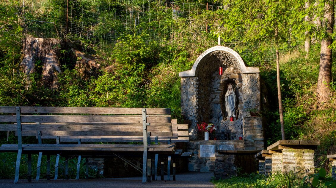 Eine kleine Kapelle in der Natur mit einer Statue. Bänke laden zum Verweilen ein. | © Kurkommission Bad Blumau