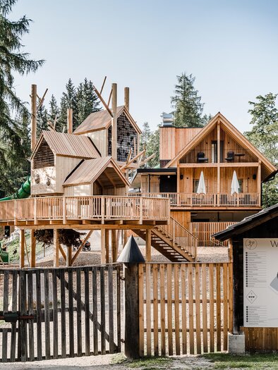 Ein Holzhaus im Wald, das modern und einladend aussieht. Neben dem Gebäude steht ein Informationsschild zum Waldpark Hochreiter. | © Waldpark Hochreiter