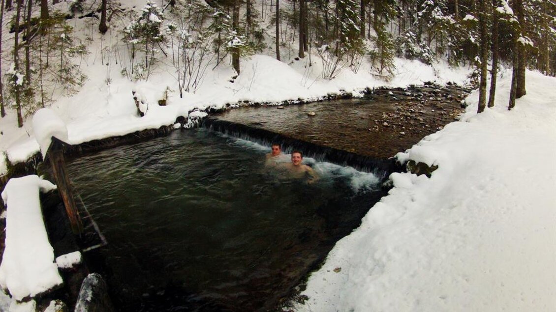 Ein schwimmender Bereich in einem schneebedeckten Wald. Zwei Personen genießen das kühle Wasser zwischen schneebedeckten Bäumen. | © Tourismusverband Gesäuse