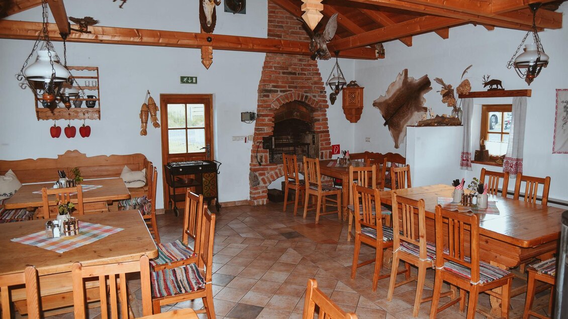 Ein gemütliches Restaurant mit Holzmöbeln und einem offenen Kamin. Die Wände sind mit traditionellen Dekorationen geschmückt. | © Lederer