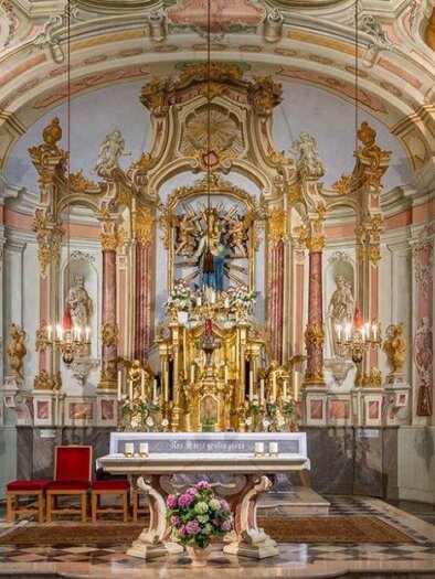 A beautiful church with an richly decorated altar and intricate wall paintings. The atmosphere is peaceful and inviting. | © Romana Maier