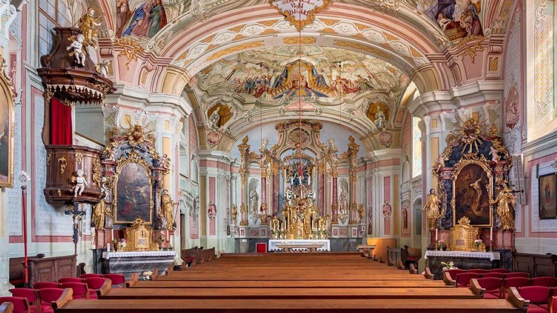 Eine prächtige Kirche mit aufwendiger Deckenmalerei und kunstvollen Altären. Die Bänke aus Holz sind ordentlich aufgereiht und laden zum Sitzen ein. | © Romana Maier