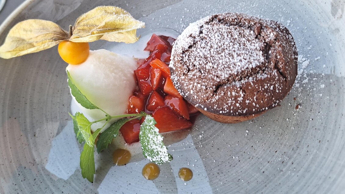 Saftiger Schokoladen-Muffin im Walter's Genusswirt in Voitsberg, begleitet von frischen Beeren, erfrischendem Sorbet und einer dekorativen Physalis. | © Walter Prettenthaler