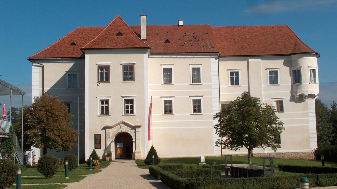 Ein historisches Schloss mit einem roten Satteldach und großen Fenstern. Der gepflegte Garten um das Gebäude ergänzt die elegante Architektur. | © Marktgemeinde Burgau