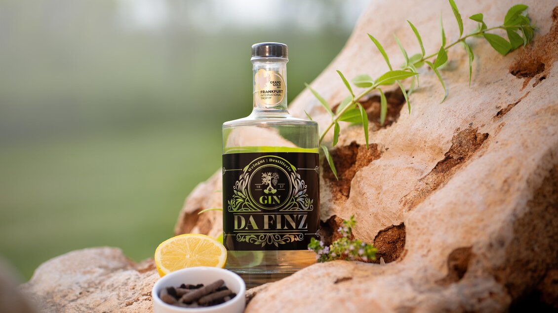 Flasche Gin vom Weingut Destillerie Da Finz in Mooskirchen auf einem Naturstein mit Gewürzen und Zitrone. | © Weingut Destillerie Da Finz