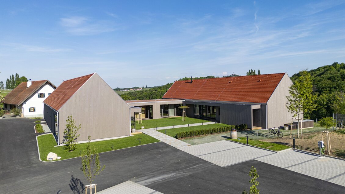 Ein modernes Wohnhaus mit roten Dächern und großzügigen Grünflächen. Die Umgebung ist gut gestaltet mit gepflasterten Wegen und Bäumen. | © BU Dietrich