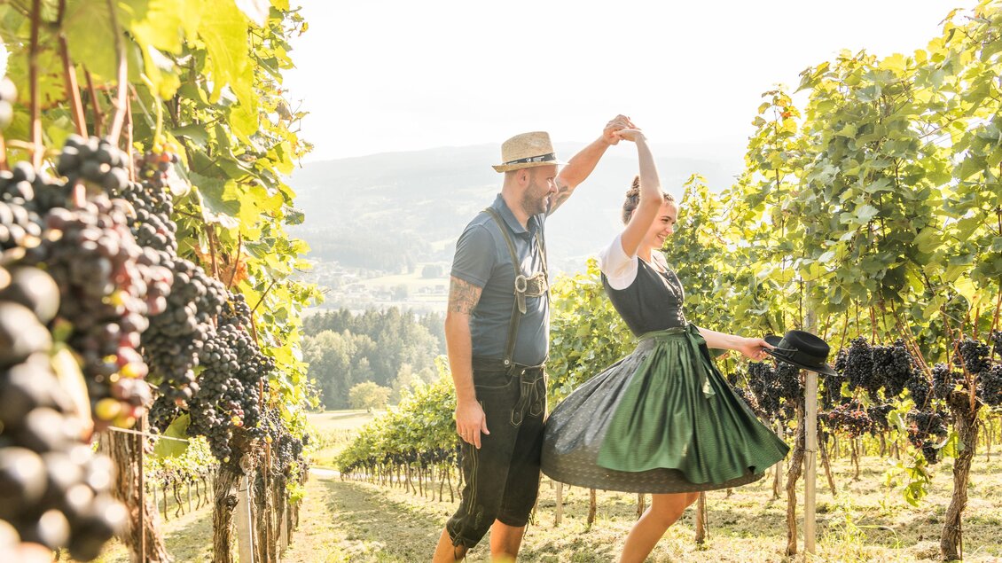 Zwei Personen tanzen zwischen den Rebzeilen im Weingarten des Weinguts Kremser-Greitbauer in Ligist. | © TV Region Graz - Die Abbilderei