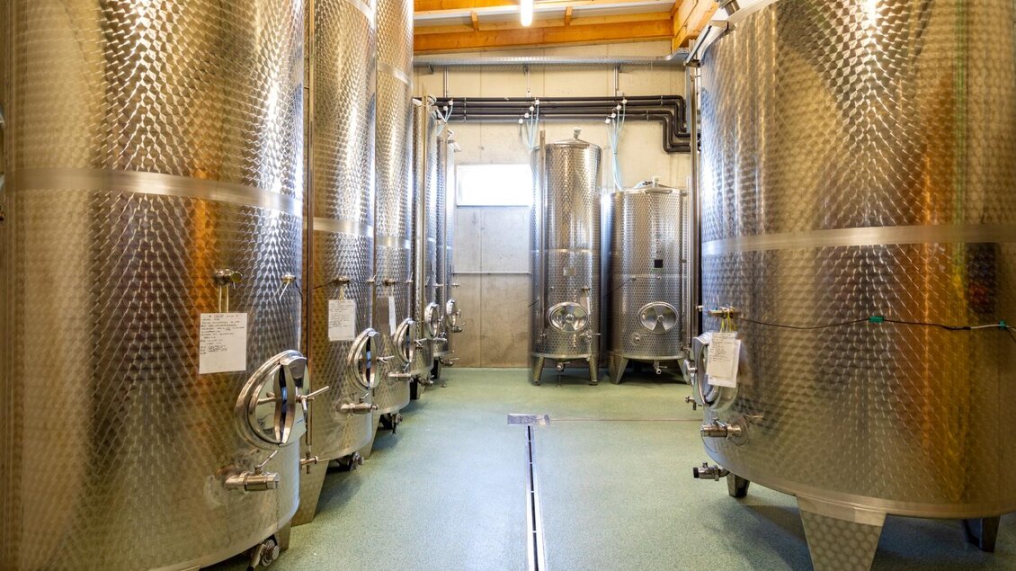 Ein modernes Weinkeller mit großen, silbernen Edelstahltanks. Die Tanks stehen in einem hellen Raum mit Holzdecken. | © Weingut Perner