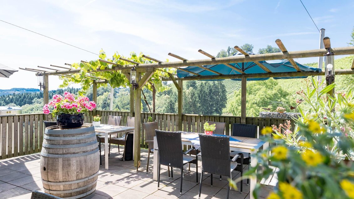 Eine gemütliche Terrasse mit Blick auf die Natur. Tische und Stühle sind gut angeordnet, um draußen zu genießen.