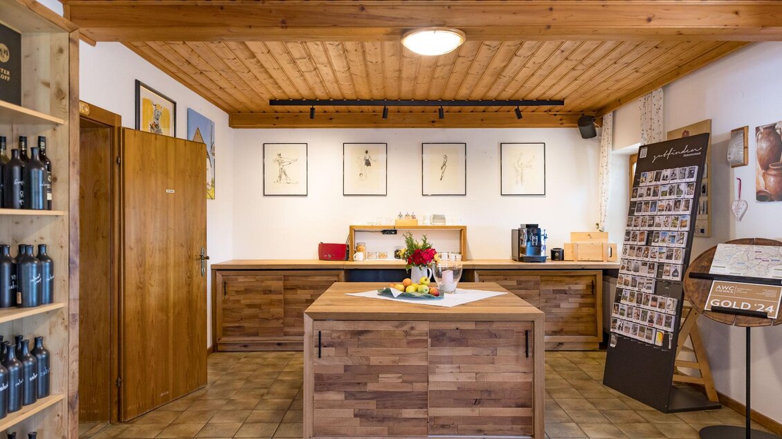 Ein einladender Empfangsbereich mit Holzmöbeln und dekorativen Bildern an der Wand. In der Mitte steht ein zentraler Tisch mit einer floral dekorierten Schale.