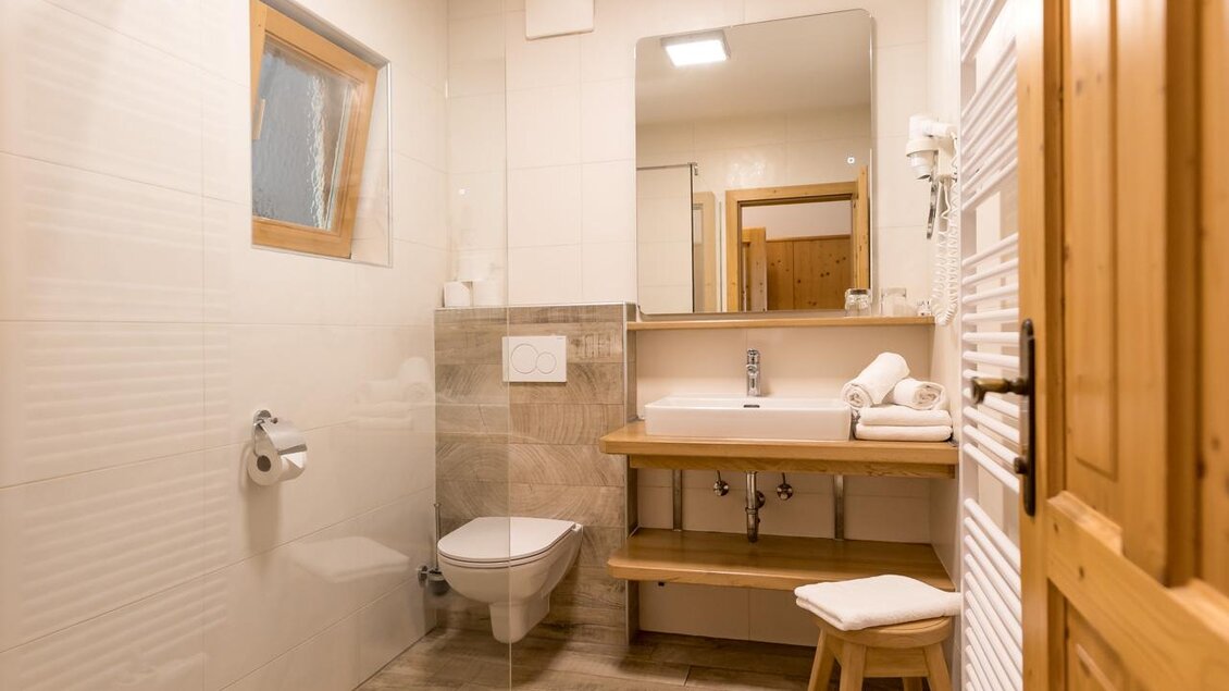 Ein modernes Badezimmer mit einer begehbaren Dusche und Holzdetails. Der Raum ist hell und bietet eine freundliche Atmosphäre.