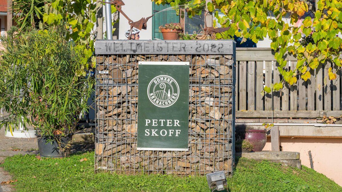 Ein Schild mit dem Namen "Peter Skoff" und der Auszeichnung "Weltmeister 2022". Im Hintergrund sind Pflanzen und eine Holzverkleidung sichtbar.