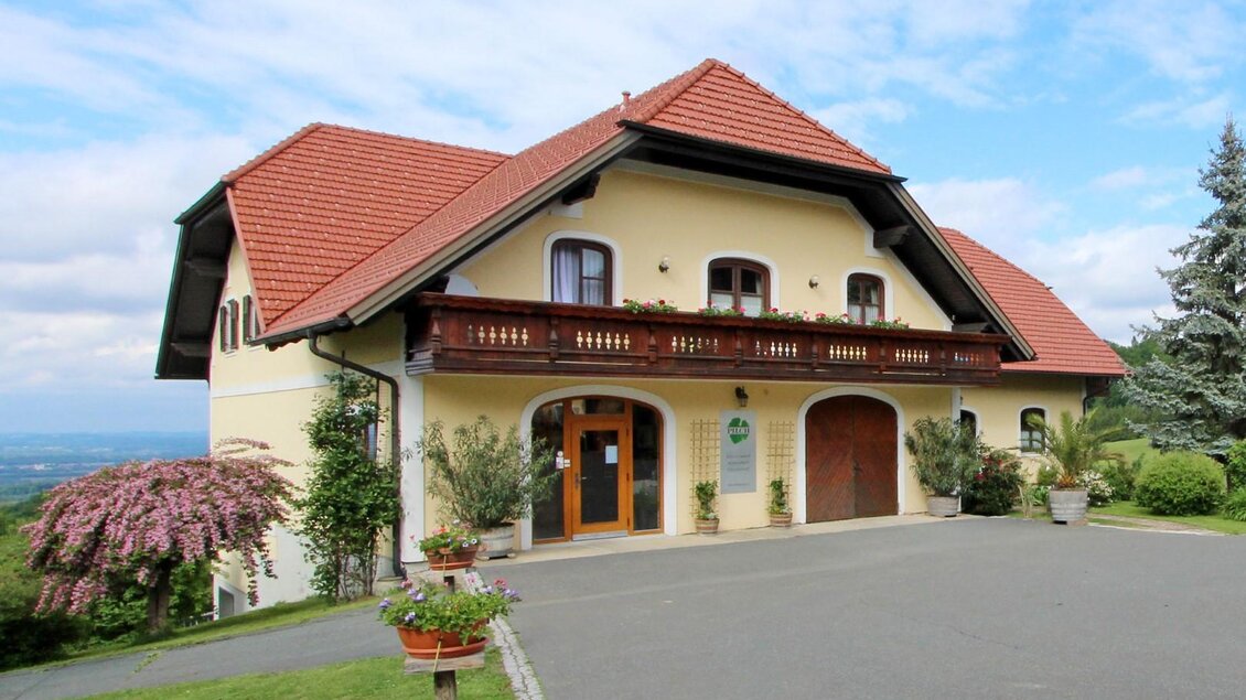 Ein hübsches Landhaus mit rotem Dach und Balkonen. Die Umgebung ist grün und blühend, ideal für eine ruhige Auszeit. | © Weingut Pilch | Fam. Pilch