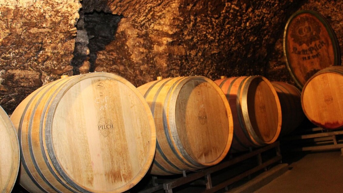 Ein Weinkeller mit Holzfässern, die auf Regalen stehen. Die Wände sind aus Stein und schaffen eine rustikale Atmosphäre. | © Weingut Pilch | Fam. Pilch