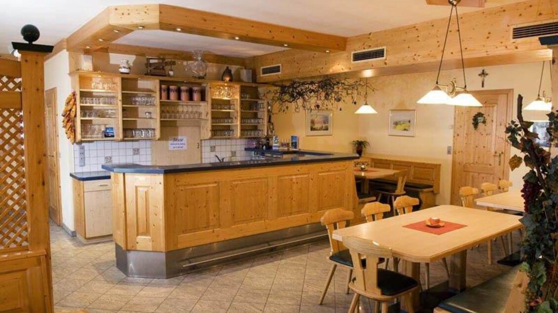 Eine gemütliche Inneneinrichtung mit Holzregalen und einer Theke. Tische und Stühle laden zum Verweilen ein. | © Weingut Reinisch