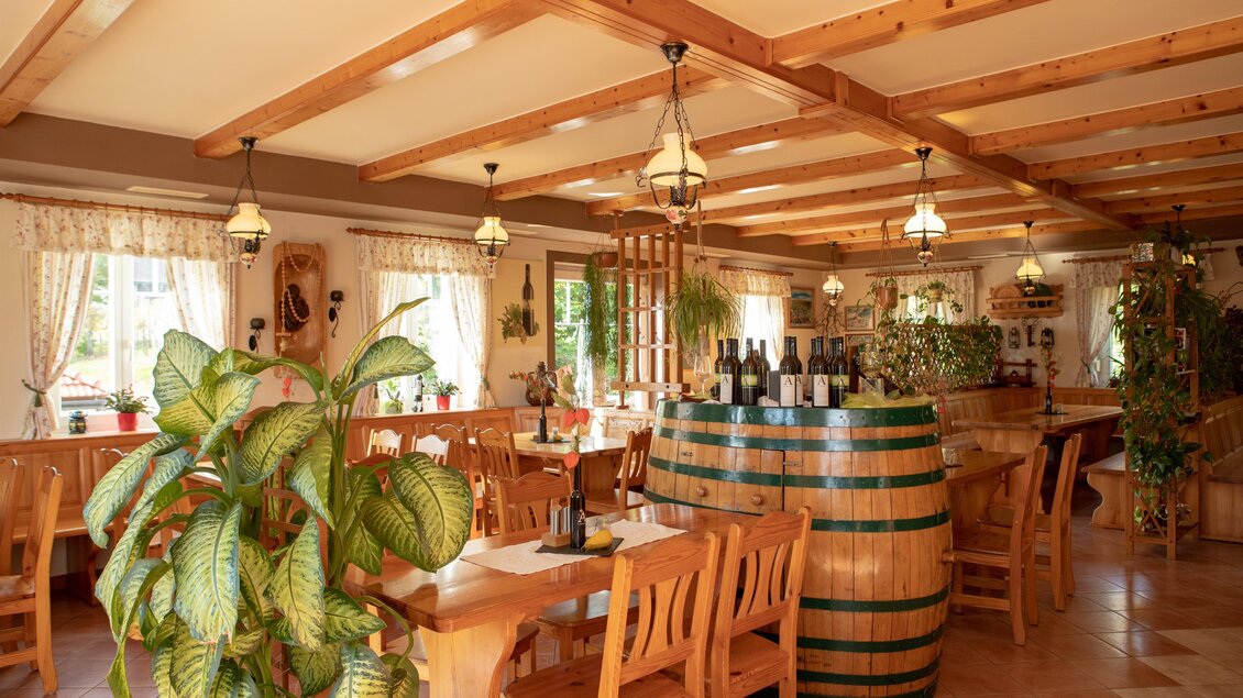 Ein gemütliches Restaurant mit Holzmöbeln und einer großen Weinfass als Tisch. Pflanzen und Fenster sorgen für eine einladende Atmosphäre. | © GlaMUR-Genuss am Fluss, Ulrike Korntheuer