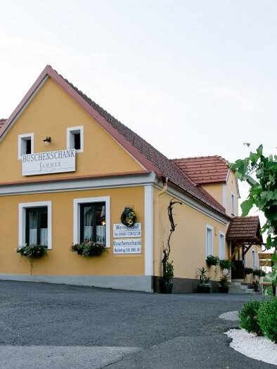 <p>Ein charmantes Gasthaus mit gelber Fassade und blühenden Fenstern. Neben dem Gebäude steht ein informatives Schild. Weinhof Sammer in Bad Loipersdorf.</p> | © Buschenschank Sammer