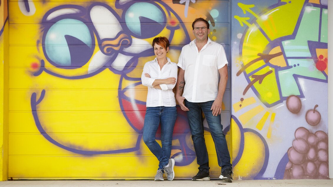 Das Ehepaar Ramminger vor Graffitihintergund | © Tourismusverband Oststeiermark