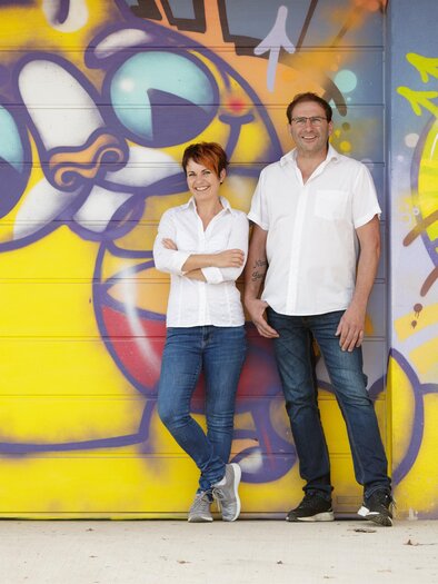 The couple Ramminger in front of a graffiti background | © Tourismusverband Oststeiermark