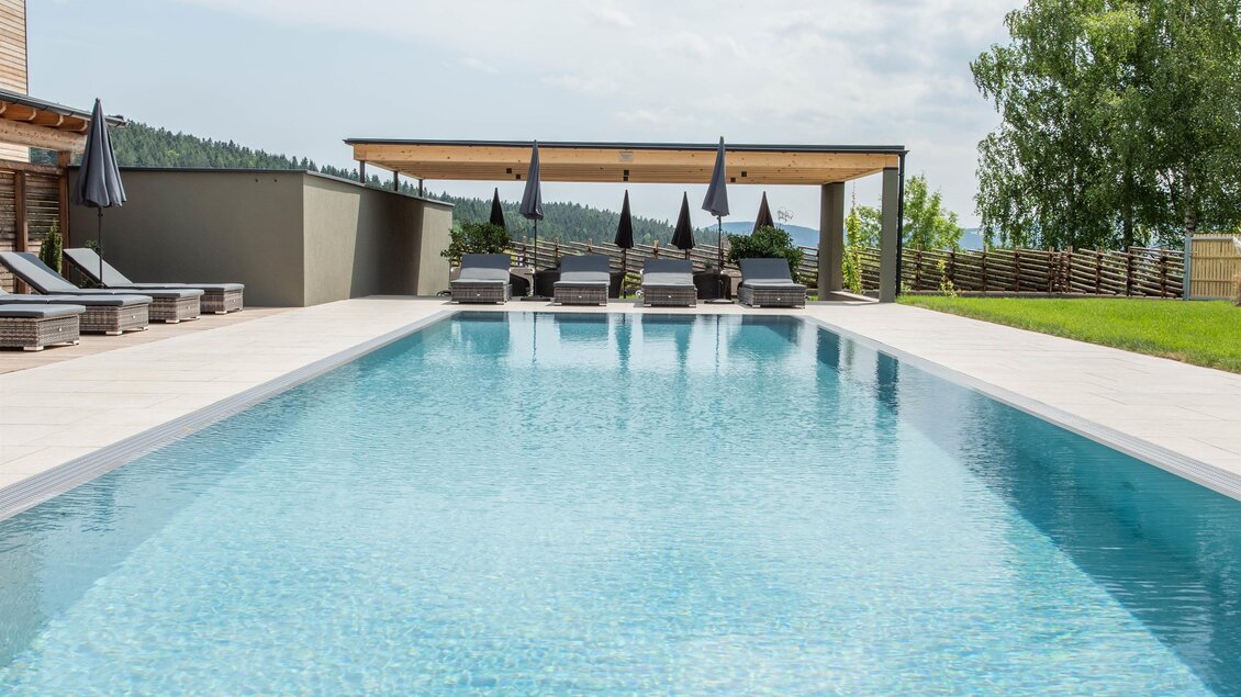 Ein schöner Swimmingpool mit klarem Wasser und Liegen am Rand. Die Umgebung ist grün und einladend unter einem teilweise bewölkten Himmel. | © Helmut Schweighofer