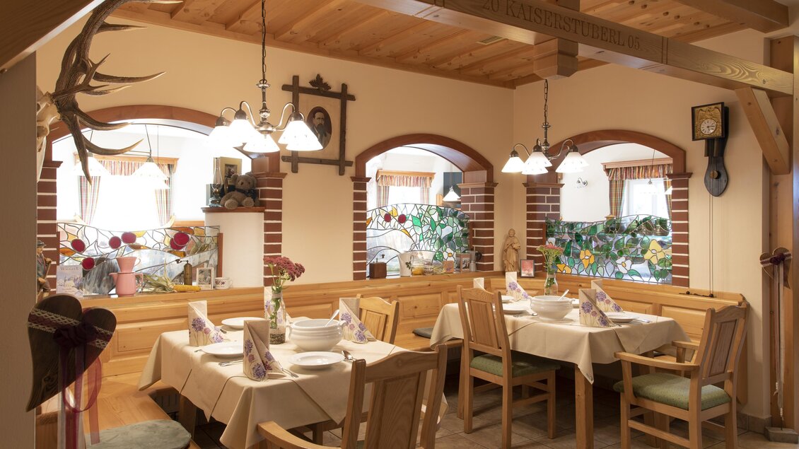 Ein gemütliches Restaurant mit Holzmöbeln und warmem Licht. Die Tische sind ordentlich gedeckt und dekoriert. | © Gasthof Orthofer