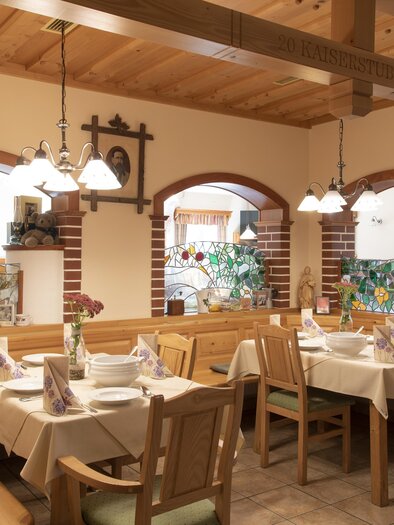 Ein gemütliches Restaurant mit Holzmöbeln und warmem Licht. Die Tische sind ordentlich gedeckt und dekoriert. | © Gasthof Orthofer