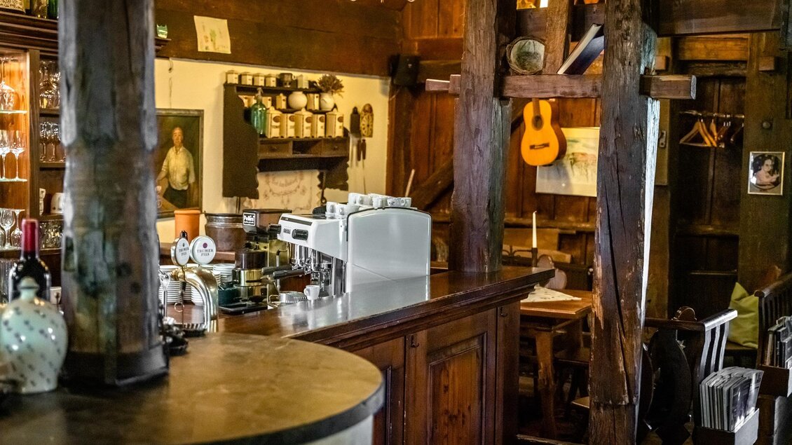 Ein gemütliches Restaurant mit Holzdekor und einer Theke. An der Wand hängen Instrumente und Bilder, die eine einladende Atmosphäre schaffen. | © Stephan Friesinger