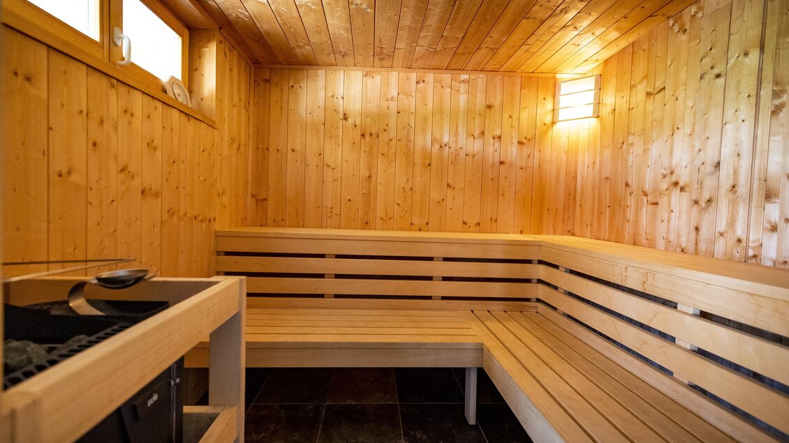 Ein gemütlicher Sauna-Raum aus Holz mit Bänken und sanfter Beleuchtung. Die Atmosphäre ist entspannend und einladend. | © Winzerhof Strablegg