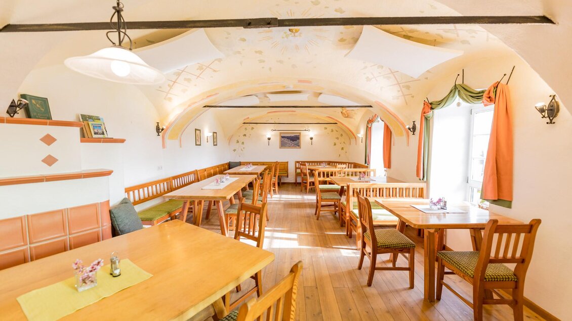 Ein einladender Speisesaal mit Holztischen und Stühlen. Die gemütliche Atmosphäre wird durch die warmen Farben und die dekorativen Elemente unterstrichen. | © Winzerhof Strablegg