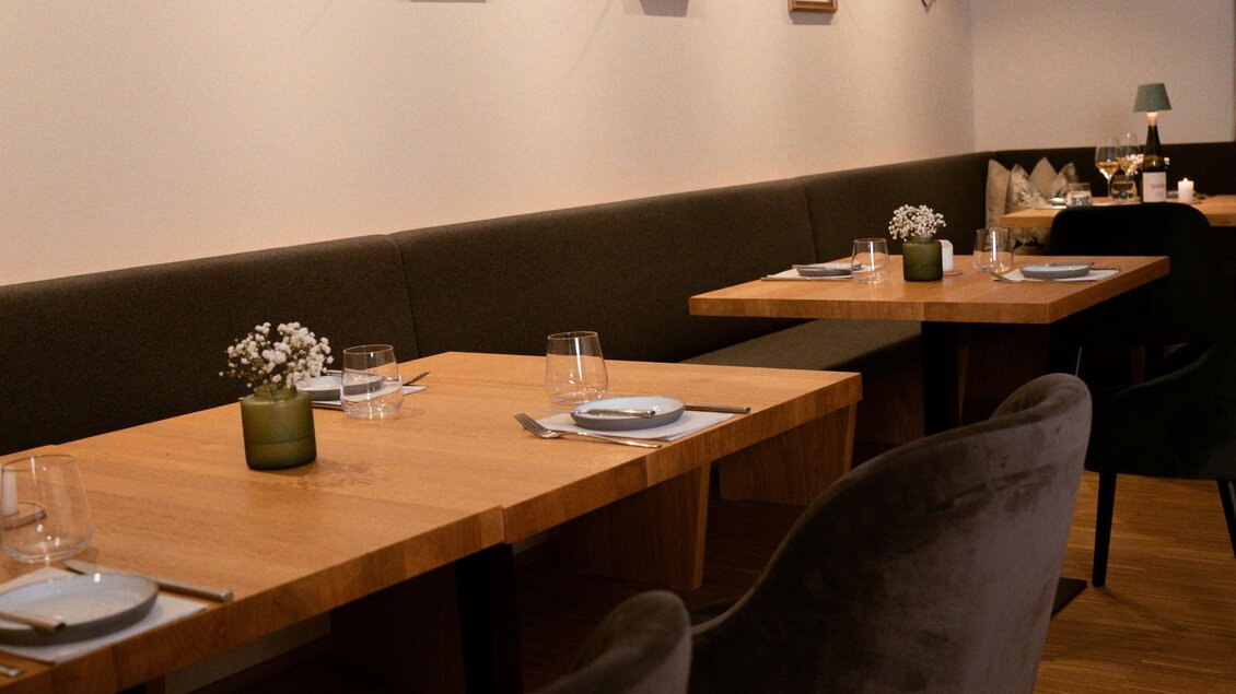 Ein stilvolles Restaurant mit Holztischen und eleganten Stühlen. An den Wänden hängen Bilder, die das Ambiente gemütlich gestalten. | © Das Weinkitz