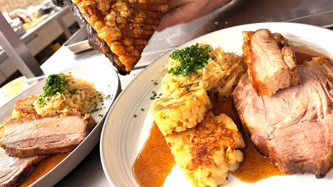 <p><p>Ein köstliches Gericht mit zartem Fleisch, knuspriger Kruste und Beilagen. Auf den Tellern sind auch Sauerkraut und Serviettenknödel zu sehen.</p></p> | © Wirtshaus zum Römerstein