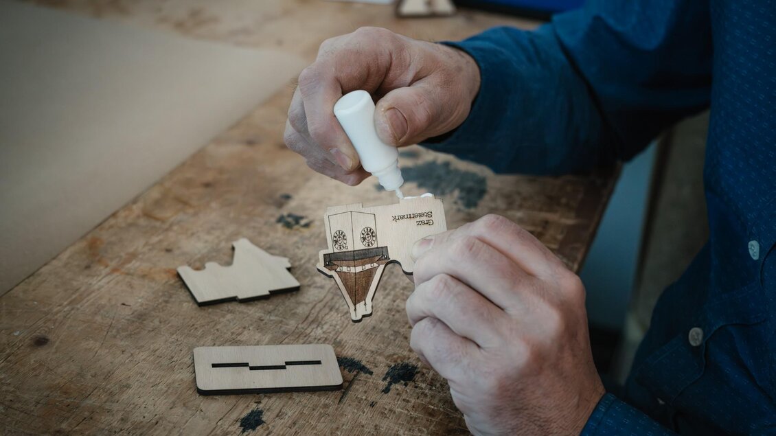 Von Hand wird der Klebstoff auf ein graviertes Holzteil aufgetragen und setzen ein kleines Holzobjekt von WoodHeroes zusammen. | © Bernd Grosseck