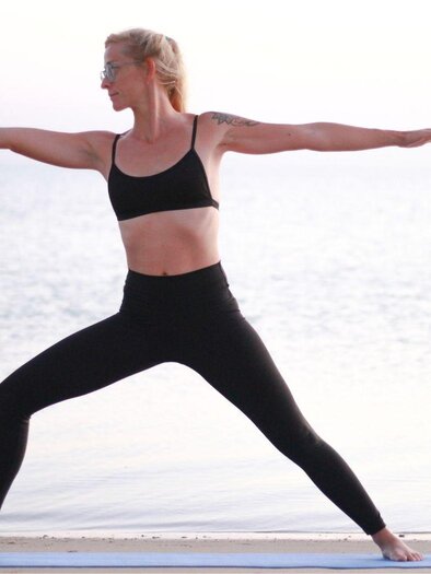Kiki Höglinger from Yoga mit Kiki practices a classic yoga exercise against a calm background. | © Kiki Höglinger