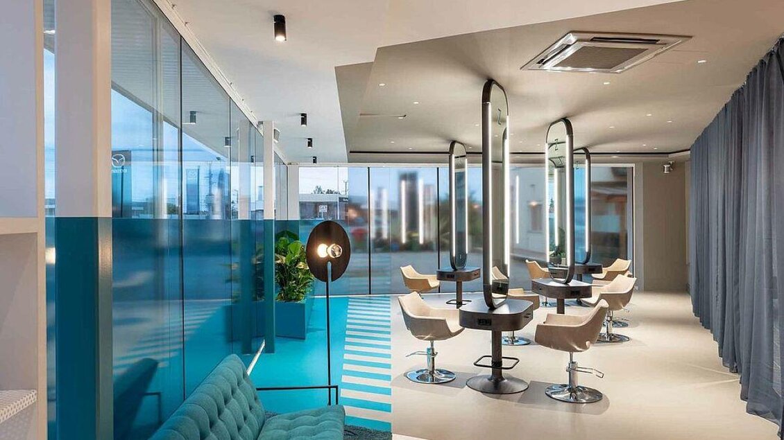 Ein modernes Wohnzimmer mit eleganten Möbeln und großen Fenstern. Die hellen Farben und das stilvolle Design schaffen eine einladende Atmosphäre. | © Zeitgeist Frisiersalon