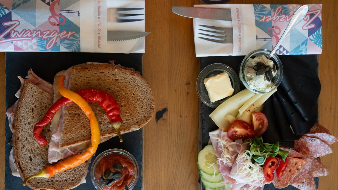 Ein schön angerichtetes Brett mit Brot, Schinken und buntem Gemüse. Daneben eine Auswahl an Käsesorten und Wurst mit frischem Gemüse. | © STG