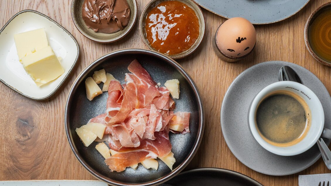 Ein reichhaltiges Frühstücksensemble mit Croissants, frischem Obst, Schinken, Käse und Müsli. Dazu gibt es Kaffee und verschiedene Aufstriche. | © Das Ursprung